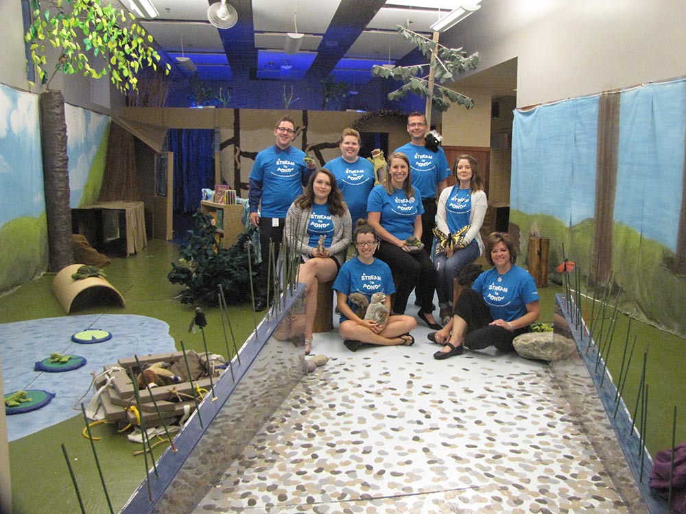 A group of museum employees standing in the entryway of the Stream to PONDer exhibit at the Children's Museum. 