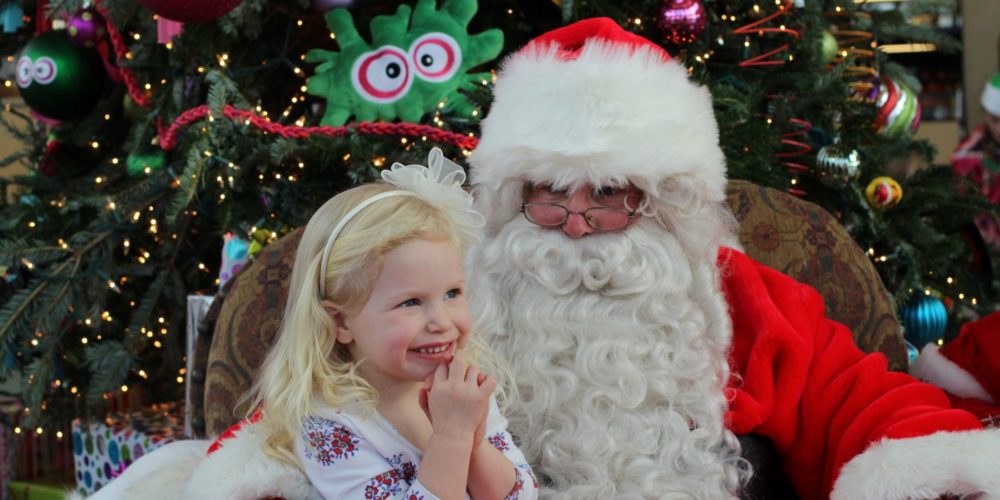 Girl sitting on Santa's lap smiling.