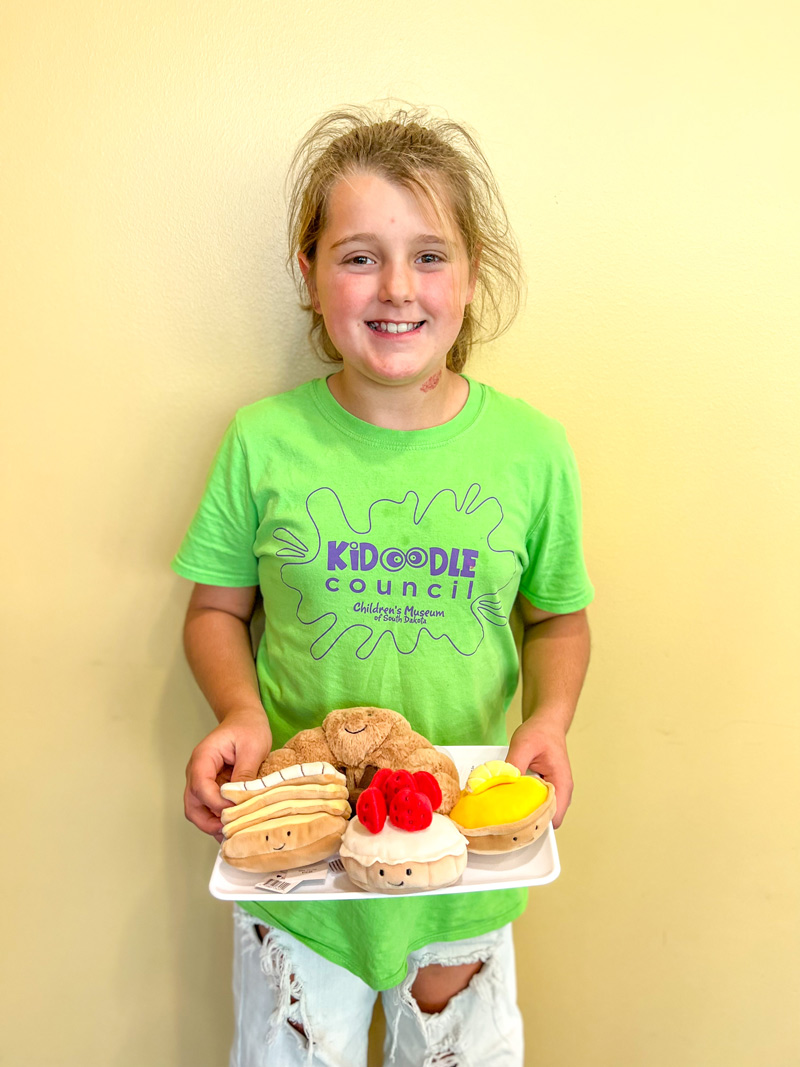 girl holding a tray of plush desserts
