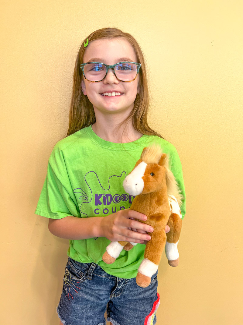 girl holding a horse plush