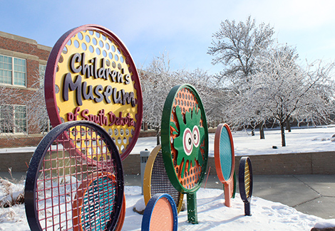 Children's Museum sign with frost on a snowy blue-skied day.