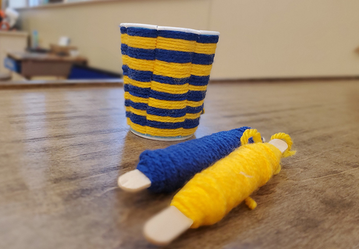 Blue and yellow woven yarn basket made out of a Dixie cup.