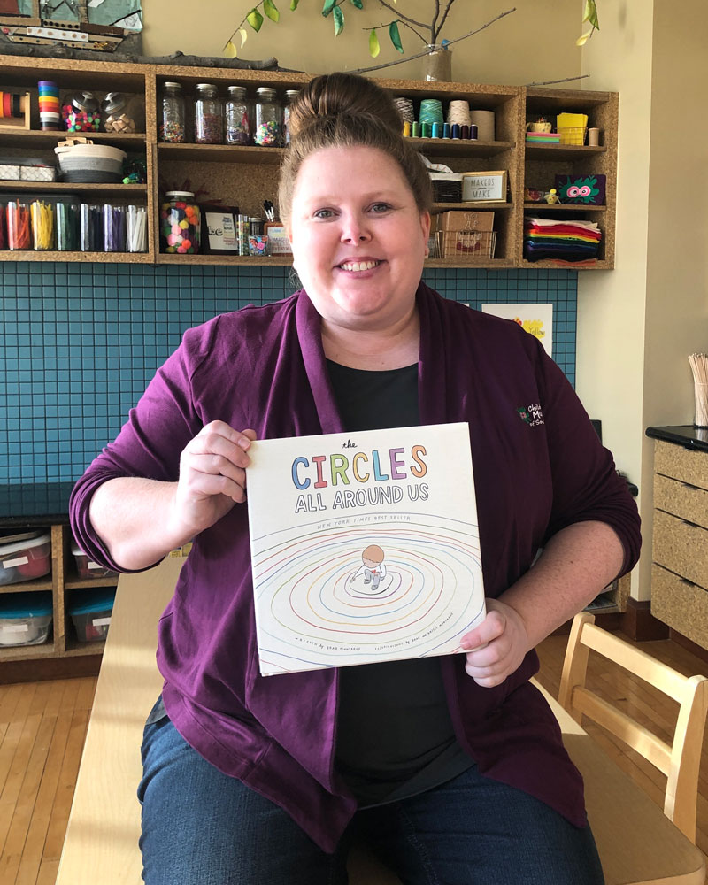 Carrie holding up the book Circles All Around Us by Brad Montague