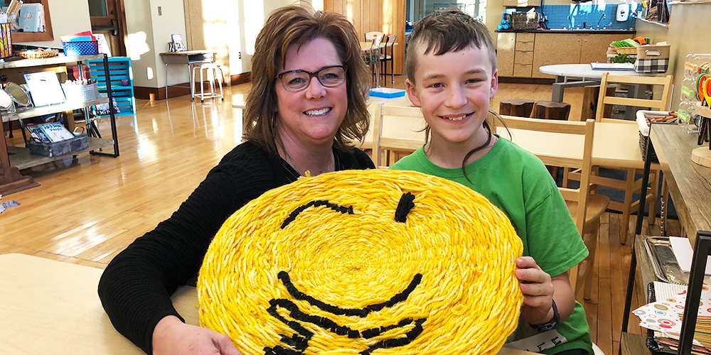 Connor shares his completed art project with Executive Director Kate Treiber. 