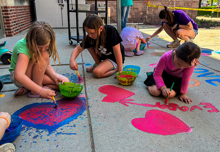Friends outside chalk painting on sidewalk
