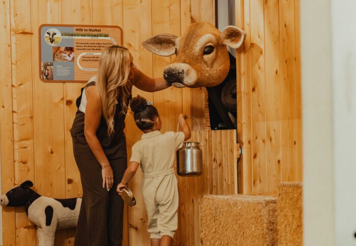 mom and daughter feeding the a cow in the farm barn